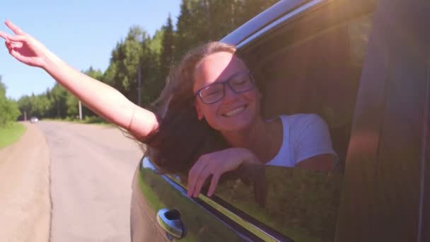 Portrait d'une jeune femme heureuse qui part en voyage, penchée par la fenêtre. Femme appréciant voyager en voiture