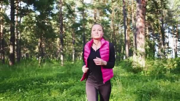Όμορφο κορίτσι που φοράει αθλητικά και τρέχει στο πράσινο δάσος στο βουνό την άνοιξη — Αρχείο Βίντεο