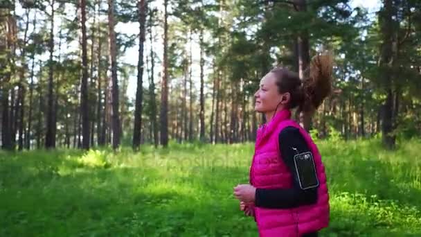 Bella ragazza che indossa abbigliamento sportivo e correre nella foresta verde in montagna durante la primavera — Video Stock