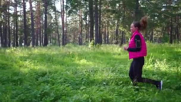 Menina bonita vestindo sportswear e correndo na floresta verde na montanha durante a primavera — Vídeo de Stock
