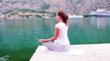 Güzel yoga arka plan üzerinde Denizi'nin muhteşem manzaralı, kusursuz bir beden ile oldukça sağlıklı kadın stand yoga poz birinde
