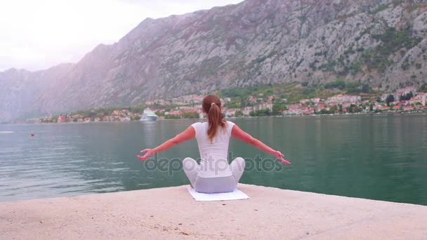Красива йога з дивовижним видом на море на фоні, досить здорова жінка з ідеальним тілом стоїть в одній з позі йоги — стокове відео