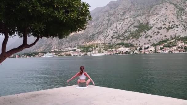 Vackra yoga med fantastisk utsikt över havet på bakgrund, ganska frisk kvinna med perfekt kropp står i en av yogaställning — Stockvideo
