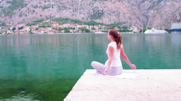 Krásný jógy s úžasným výhledem na moře na pozadí, docela zdravá žena s dokonalým tělem stojí v jednom z pozice jógy — Stock video