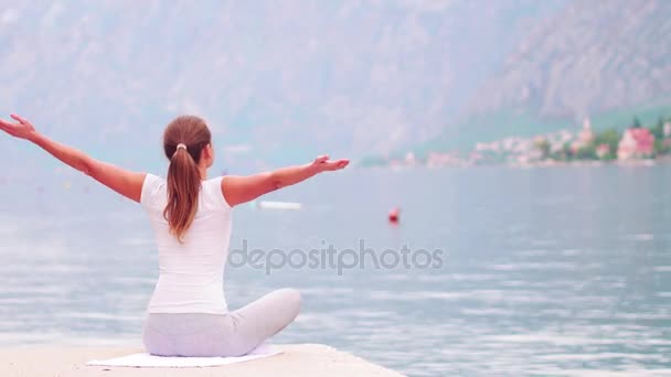 Hermoso yoga con increíble vista al mar sobre fondo, mujer bastante saludable con cuerpo perfecto de pie en una de pose de yoga — Vídeos de Stock