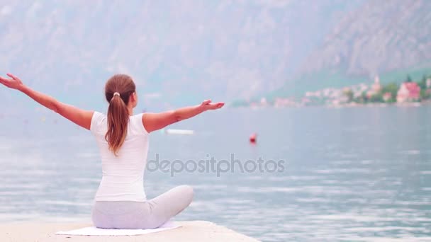 Vackra yoga med fantastisk utsikt över havet på bakgrund, ganska frisk kvinna med perfekt kropp står i en av yogaställning — Stockvideo