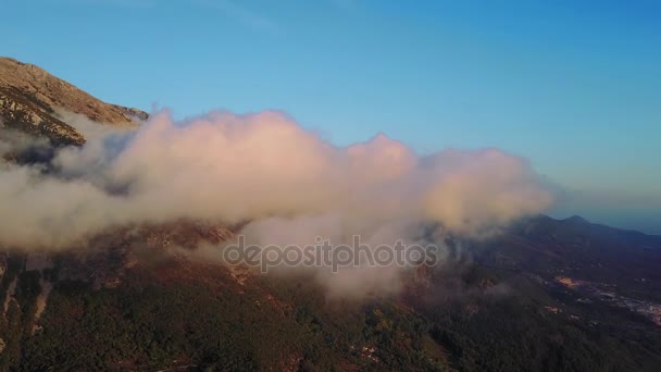 Η κάμερα κινείται μέσα από σύννεφα στα βουνά. Υπέροχη ονειρική Ανατολή του ηλίου πάνω σε βραχώδες βουνό με θέα στην κοιλάδα του misty. — Αρχείο Βίντεο