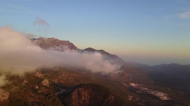 Камера рухається крізь хмари в горах. Фантастичний схід сонця на скелястій горі з видом на туманну долину . — стокове відео