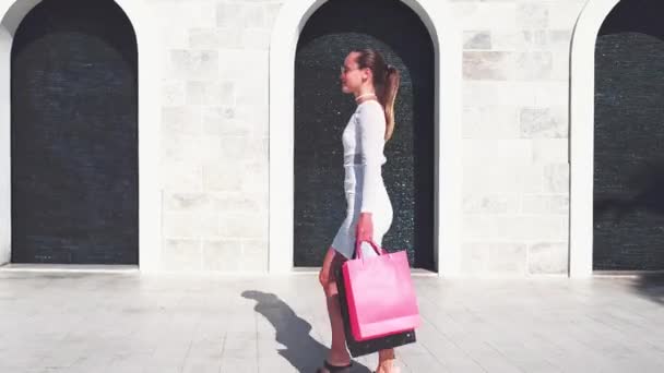 Hermosa chica feliz va de compras en la ciudad . — Vídeo de stock