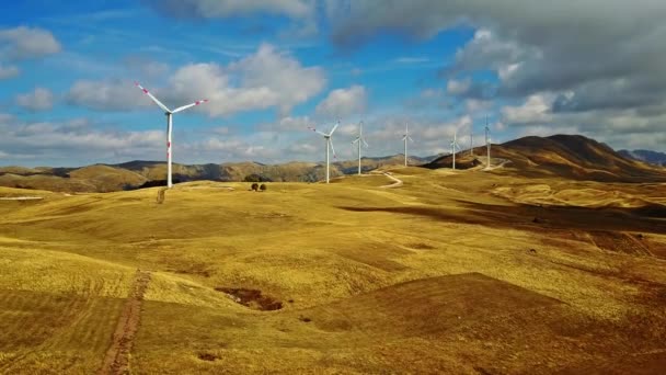 Luchtfoto zonne-boerderij en Turbines in Europa zonnepanelen energie bij zonsondergang met de bergen op de achtergrond. — Stockvideo