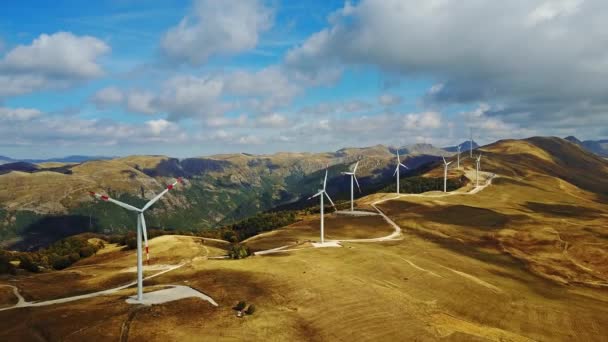 Ferme solaire aérienne et turbines en Europe Panneaux solaires énergie au coucher du soleil avec des montagnes en arrière-plan . — Video