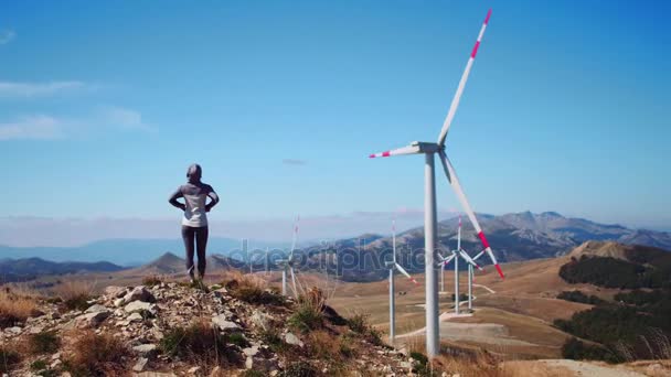 Dívka při pohledu na poli s větrnými mlýny. Žena v horách na větrné mlýny