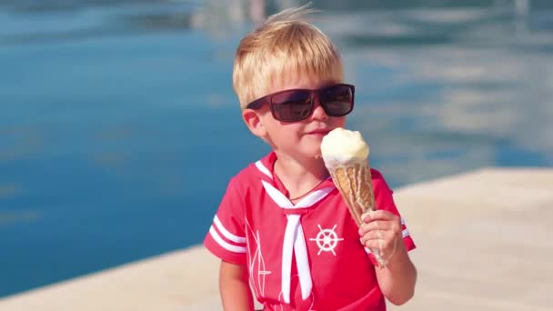 Primer plano del niño con gafas de sol comiendo helado en el puerto deportivo — Vídeos de Stock