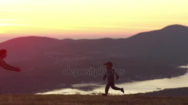 Chico corriendo a su amarradero al atardecer en las montañas — Vídeo de stock