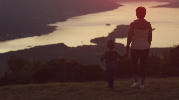 Mutter und Sohn blicken auf den Sonnenuntergang in den Bergen — Stockvideo