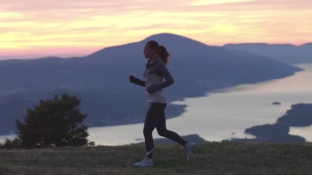 Correr - corredora corriendo al atardecer. Fitness spot chica entrenando en sol soleado con destellos y resplandor solar . — Vídeo de stock