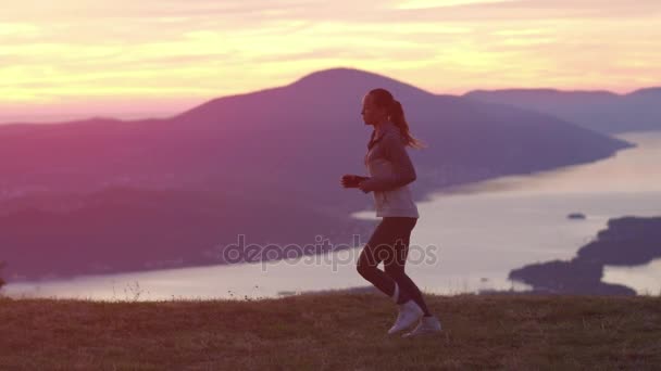 スローモーション。夕暮れ時ジョギング女性ランナーを実行しています。フレアと太陽の輝きと明るい日差しの中でトレーニング フィットネス スポット女の子. — ストック動画