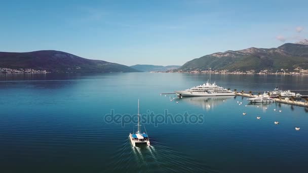 Vista aérea de barcos y hermosa arquitectura al atardecer en Europa. Paisaje colorido con barcos en la bahía marina, mar, ciudad, montañas. Vista superior desde el dron del puerto con yate y velero — Vídeo de stock