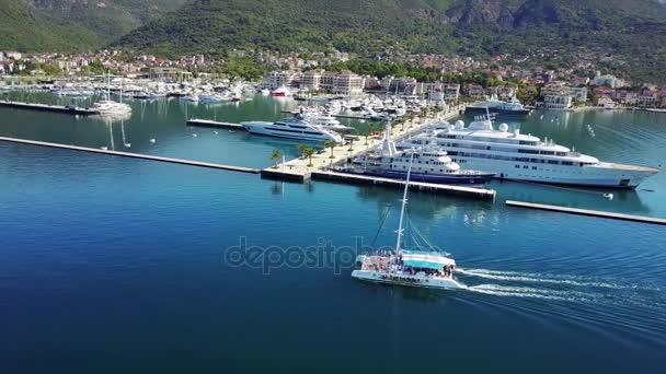 Vista aérea de barcos y hermosa arquitectura al atardecer en Europa. Paisaje colorido con barcos en la bahía marina, mar, ciudad, montañas. Vista superior desde el dron del puerto con yate y velero — Vídeo de stock