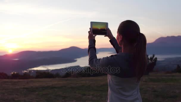 Žena tramp používají digitální tabletu s Foto v horském vrcholu útesu — Stock video