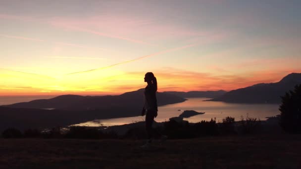 Молодая женщина, идущая на закате на вершине горы — стоковое видео