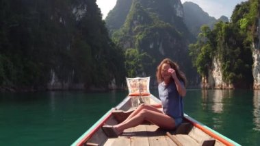 Khao Sok Milli Parkı ile vahşi doğa keşfetmek seyahat kadın merak ediyorum. Ahşap long tail tekne tropikal kireçtaşı kayalıklarla arka plan üzerinde oturuyor. Yaşam tarzı görüntü. Ada lagün.