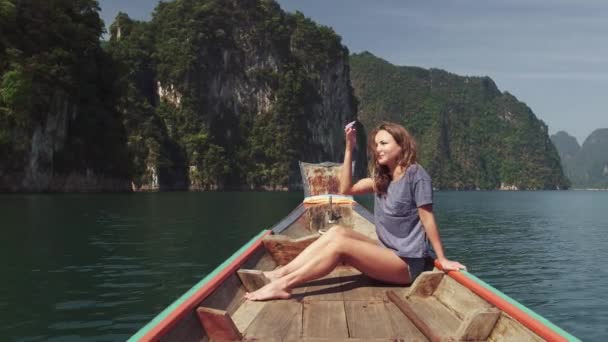 Ung Happy Mixed Race Girl Sitter och kopplar av på traditionella Thai Wooden Long Tail Boat vid Khao Sok Lake. Phang Nga-provinsen, Thailand. — Stockvideo