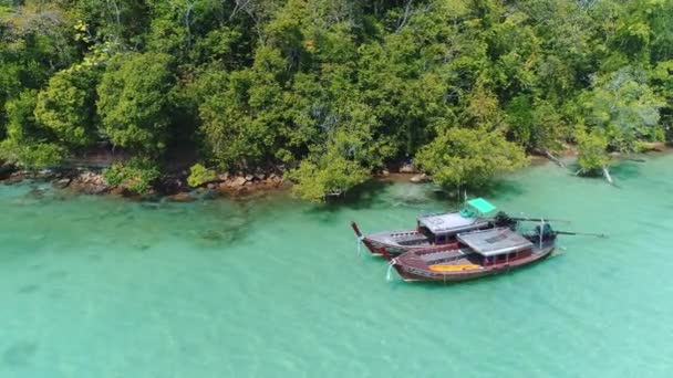 AERIAL. Drone volando bajo la increíble bahía tropical con agua clara, playa blanca y botes de cola larga tradicionales. Agua turquesa. Isla Paradaise, Tailandia. — Vídeo de stock