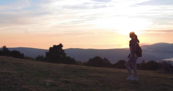 Utazó sétál a hegyek felé vezető úton. Egy nő sétál a hegyi úton naplementekor.. — Stock videók