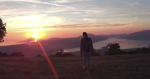 Mujer turista joven está caminando en la parte superior del montaje y mirando un hermoso paisaje de la bahía del mar. Mujer senderista con mochila relajándose en la cima del acantilado disfrutando de vistas al mar iluminadas por el sol . — Vídeo de stock