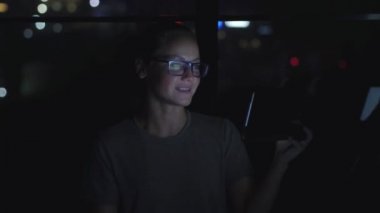 Gözlüklü kadın pencerenin yanında video konferansında konuşuyor. Arkaplanda Bokeh