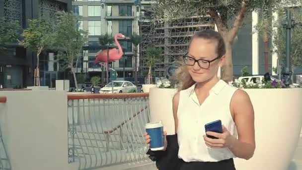 Happy woman texting on the smartphone. Executive working with a mobile phone in the street with office buildings in the background — 비디오