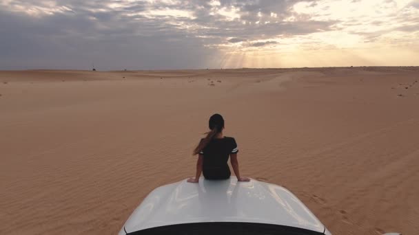Junge Reisende Frau sitzt auf dem Auto in der Wüste. Reisekonzept. — Stockvideo