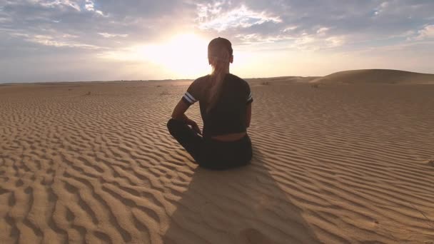 Mujer sentada en dunas de arena roja observando atardecer en Omán — Vídeos de Stock