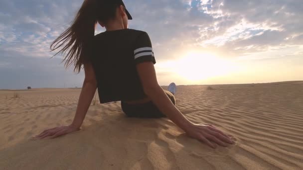 Frau sitzt auf roten Sanddünen und beobachtet den Sonnenuntergang in der Wüste — Stockvideo