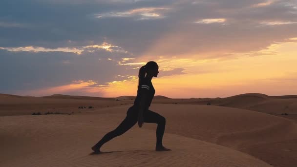 一个年轻女子日落时在广阔的沙漠里做瑜伽的轮廓。 史诗日落和体育概念视频. — 图库视频影像