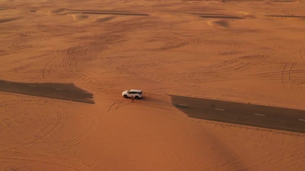 Antenne. Reisender steht an seinem Auto auf der Sandstraße in der Wüste. — Stockvideo
