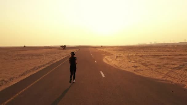 Joven mujer en forma corriendo en un camino en un desierto — Vídeos de Stock