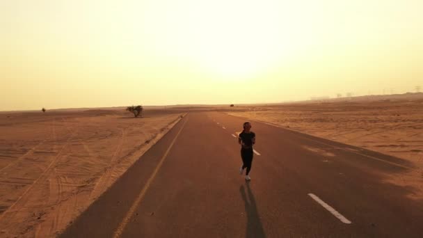 Jeune femme en forme courant sur une route dans un désert