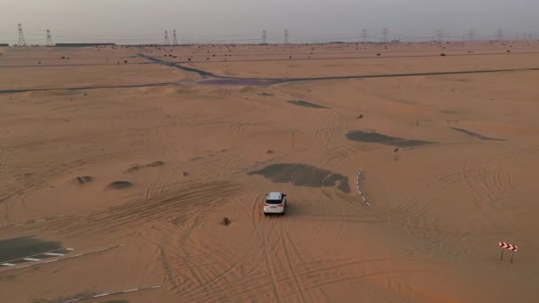 AERIAL. Vista superior del coche blanco que conduce en la carretera de los desiertos después de la tormenta de arena . — Vídeos de Stock