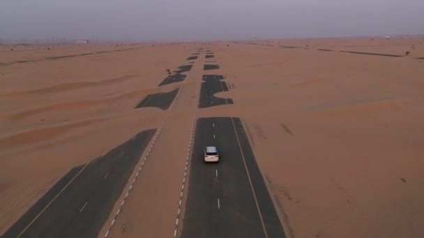 Letecký. Horní pohled na bílé auto jedoucí po silnici pouště po písečné bouři. — Stock video