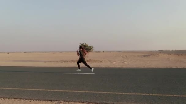 Joven mujer en forma corriendo en un camino en un desierto — Vídeos de Stock