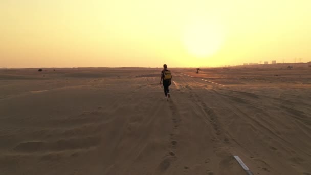 Widok z tyłu Blond włosy kobieta z żółtym autentycznym plecakiem patrząc na piaszczystej drodze po burzy piaskowej. Podróże po pustyni. — Wideo stockowe