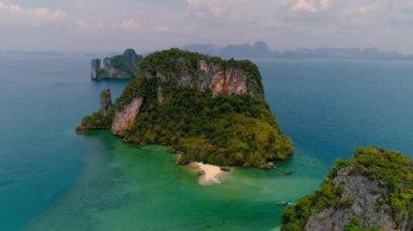 AERİAL. Günbatımında geleneksel Thai teknesi olan yeşil ada ve sahil manzarası..