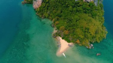 AERİAL. Günbatımında geleneksel Thai teknesi olan yeşil ada ve sahil manzarası..