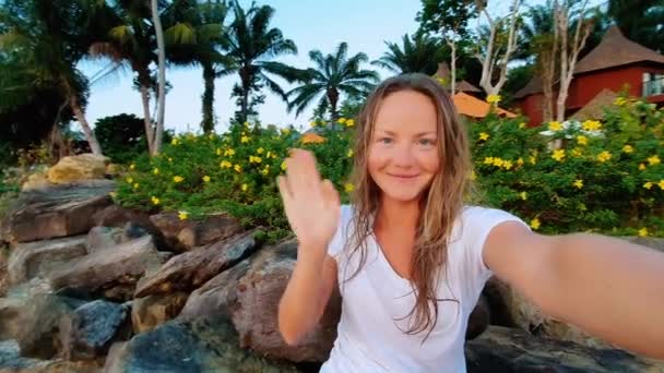 Vacances d'été voyage à la plage. Concept de technologie et de personnes avec une femme souriante faisant du selfie et shaiking main avec smartphone sur la plage . — Video