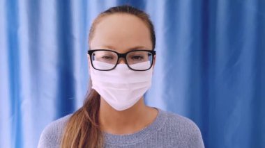 Onu virüsten korumak için tıbbi maskeli bir kız. Koronavirüs salgını. Maskeli kadın ayakta. İnsanlar hastaneye kaldırılıyor, teşhis konuyor ve Corona 'nın yayılmasını engellemek için karantina altına alınıyor..