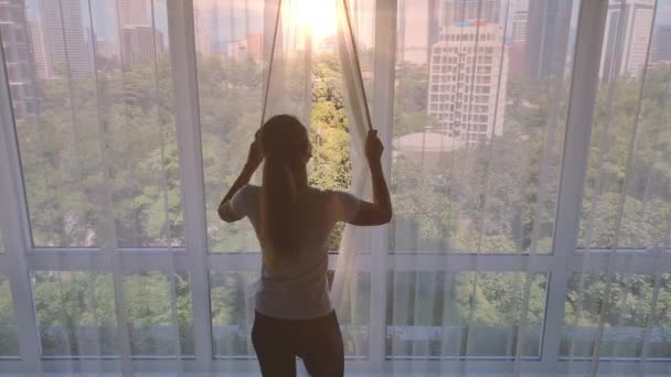 Slow motion. Young woman uncover the big window and looking out her apartment in the quarantine covid-19 time. — Stock Video