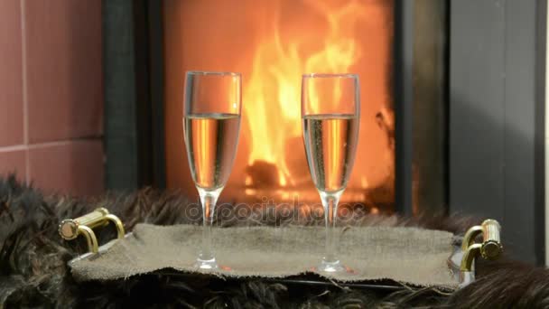 Junto a la chimenea dos copas con champán — Vídeos de Stock