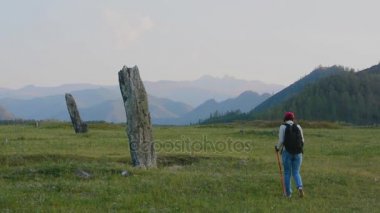 Türk dönemi antik taş stelts Altay Dağları'nda kadın turist inceliyor